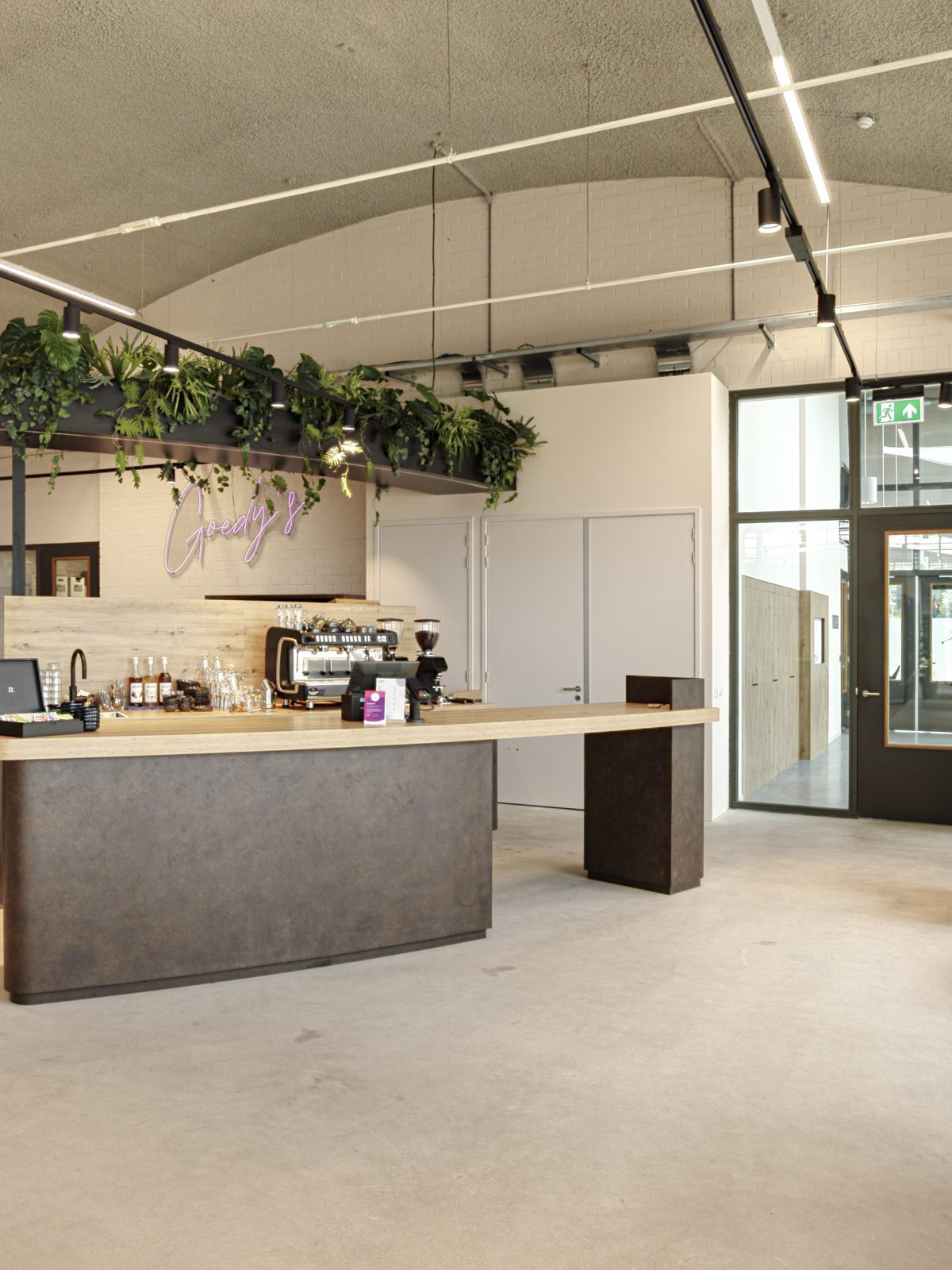 De ontvangst- en ontmoetingsruimte bij Vebego Eindhoven met een centrale balie, houten tafels en hangende planten.