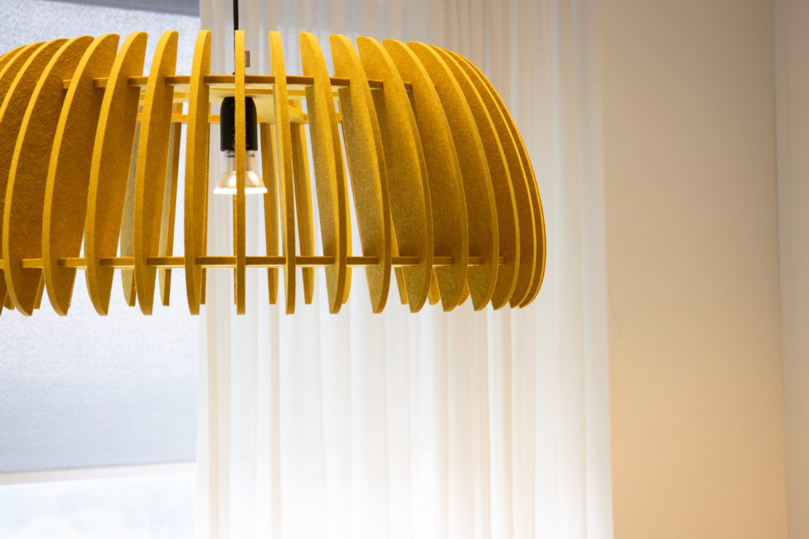 Een gele hanglamp opgebouwd uit verticale lamellen bij CLCC.