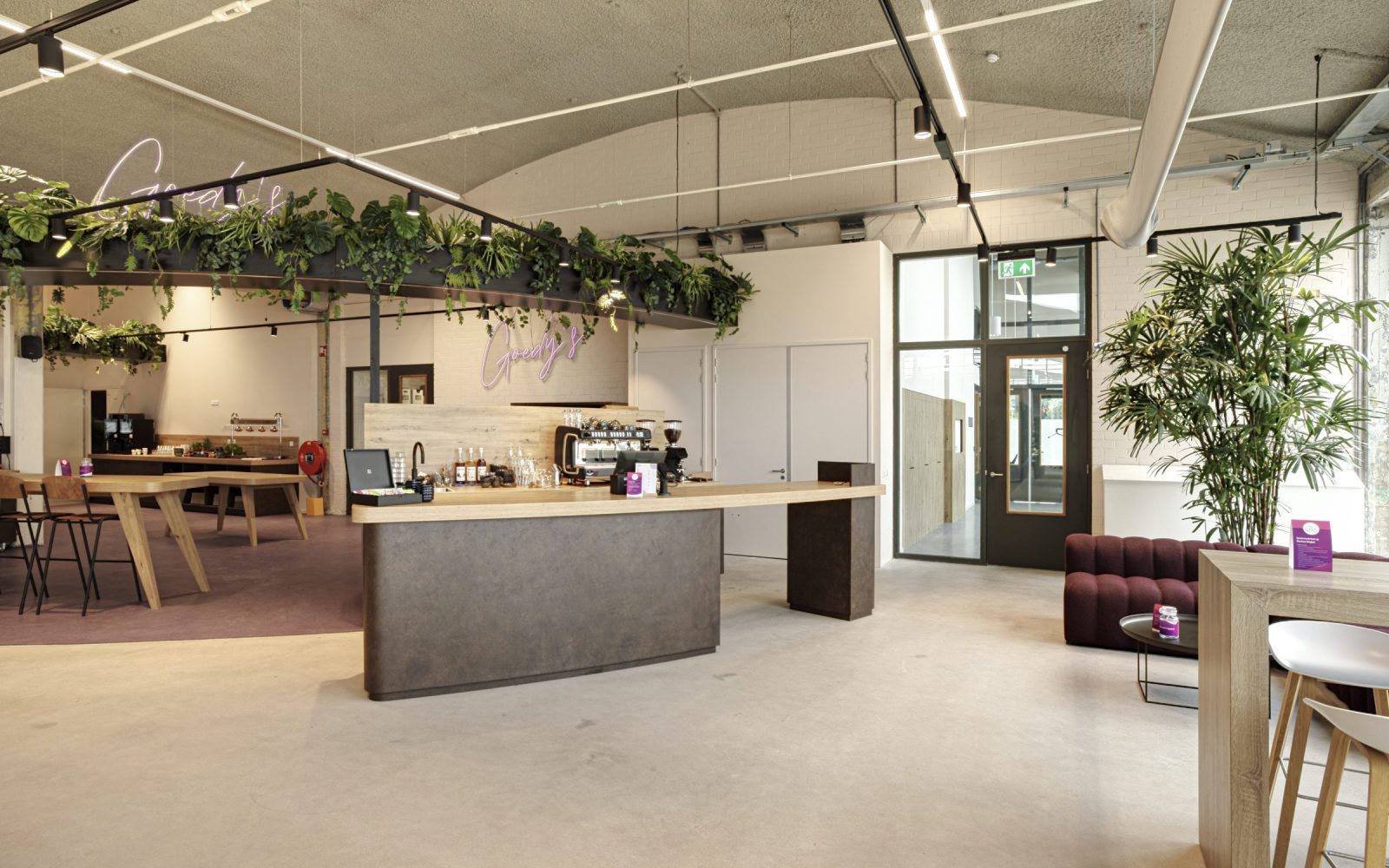 De ontvangst- en ontmoetingsruimte bij Vebego Eindhoven met een centrale balie, houten tafels en hangende planten.